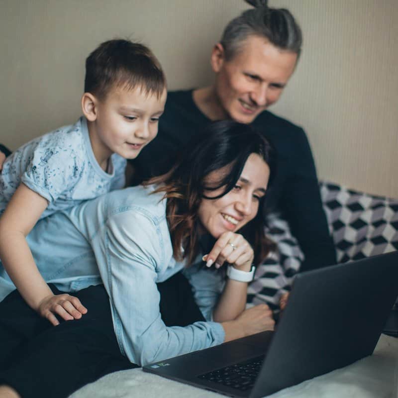 Family with computer watching live stream funeral service remotely